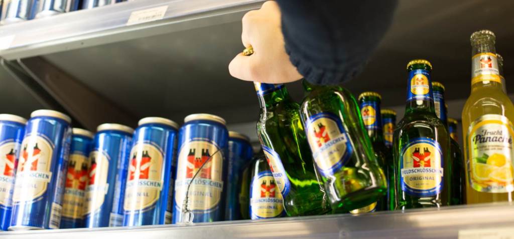 Jugendschutz Hand nimmt bei einem Alkoholtestkauf ein Bier aus einem Verkaufsregal