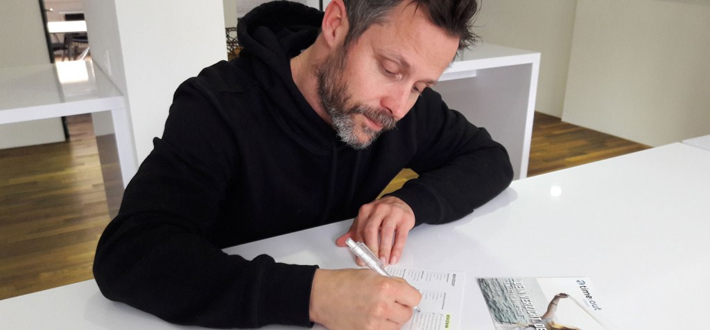 Radiomoderator Simon Mosers füllt auf einem weissen Tisch seine time:out-Anmeldung aus